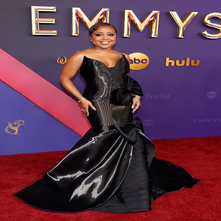 Quinta Brunson on the red carpet at the Emmys, wearing a sleek, black, form-fitting gown with a mermaid silhouette and bow details