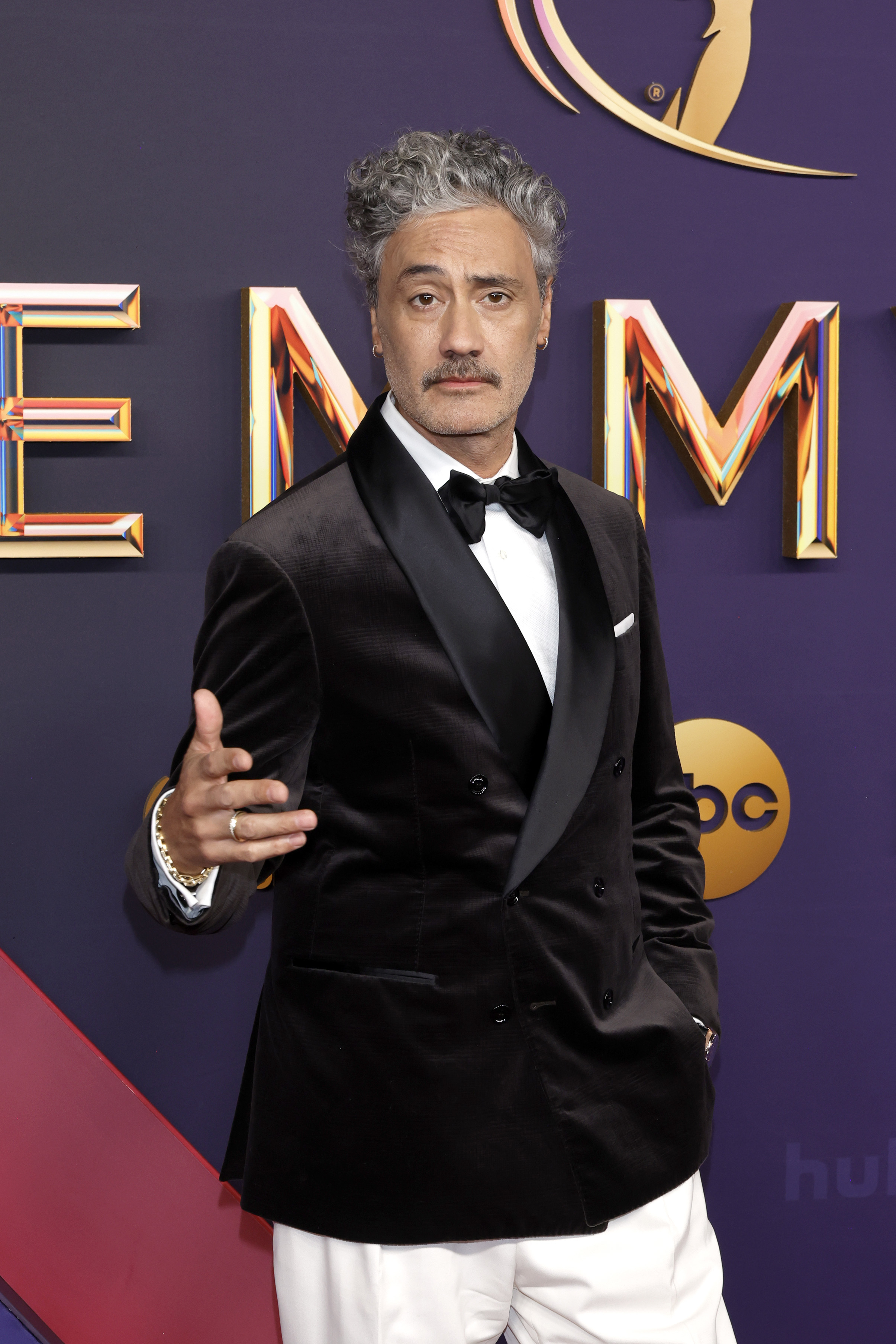 Taika Waititi dressed in a velvet tuxedo jacket with a bow tie and pants at the 2024 Emmys