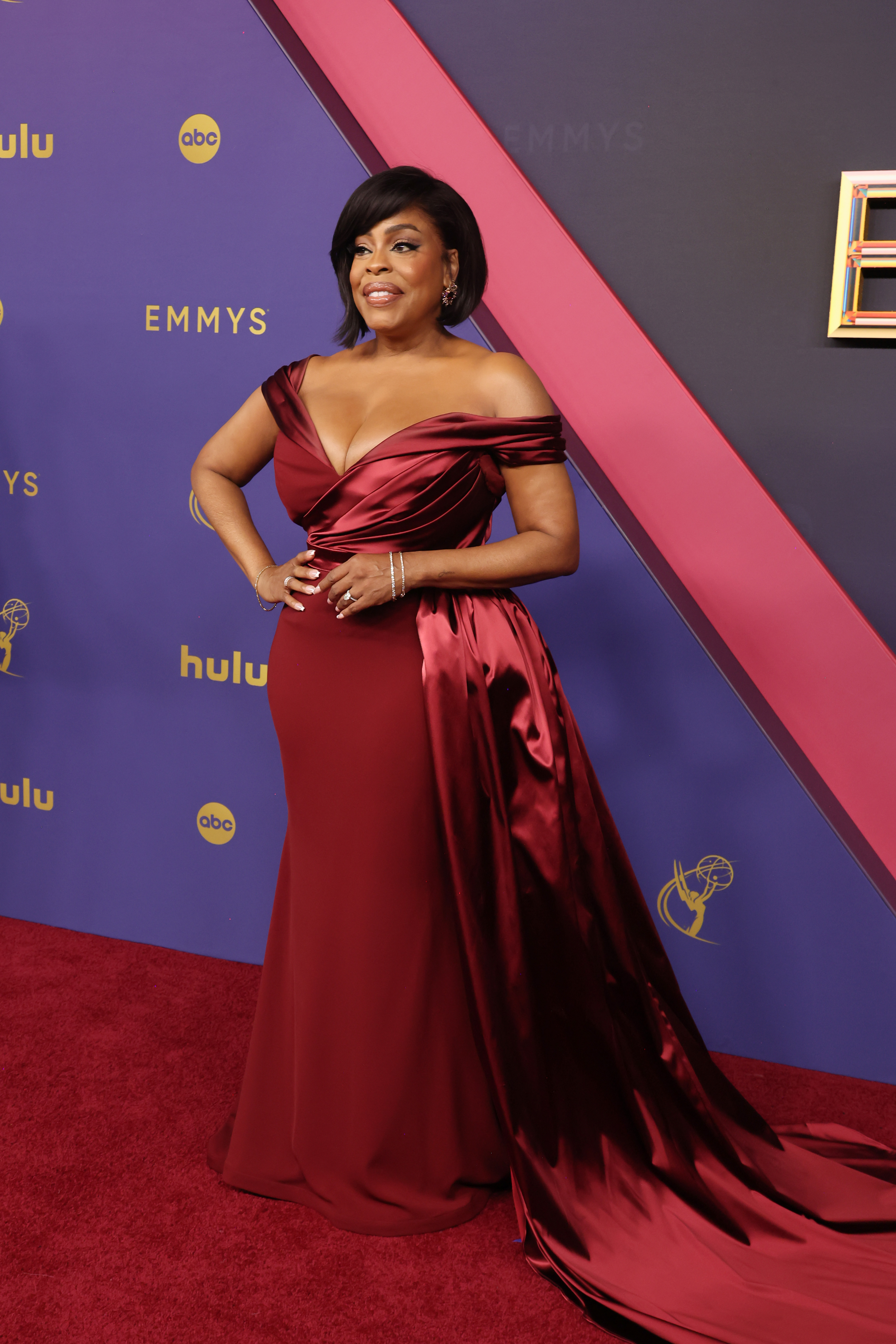 Niecy Nash poses on the red carpet at the Emmys in an elegant off-the-shoulder gown with a satin train