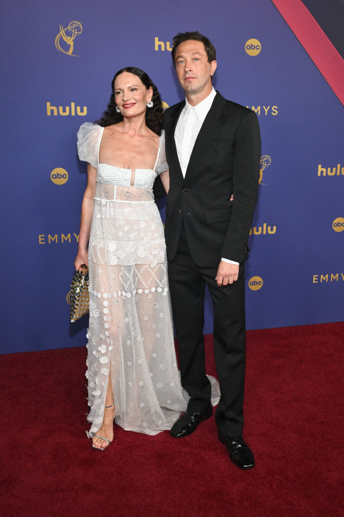 Yelena Yemchuk and Ebon Moss-Bachrach, with Yelena wearing a sheer gown with floral patterns and Ebon in a black suit and white shirt