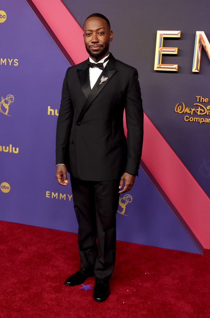 Lamorne Morris on the red carpet at the Emmys wearing a black tuxedo with a bow tie