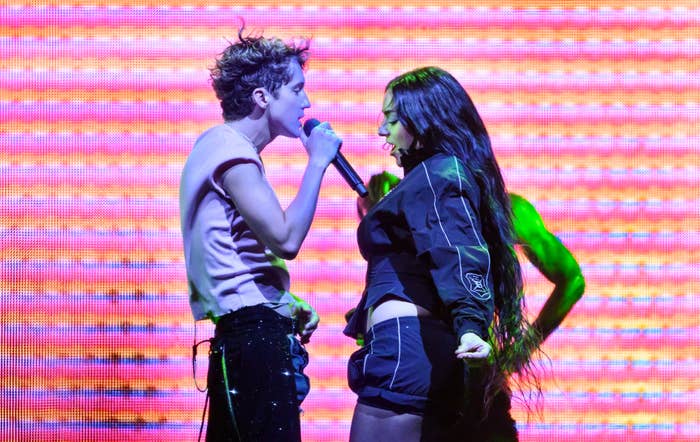 Troye Sivan and Charli XCX performing on stage with neon lights in the background