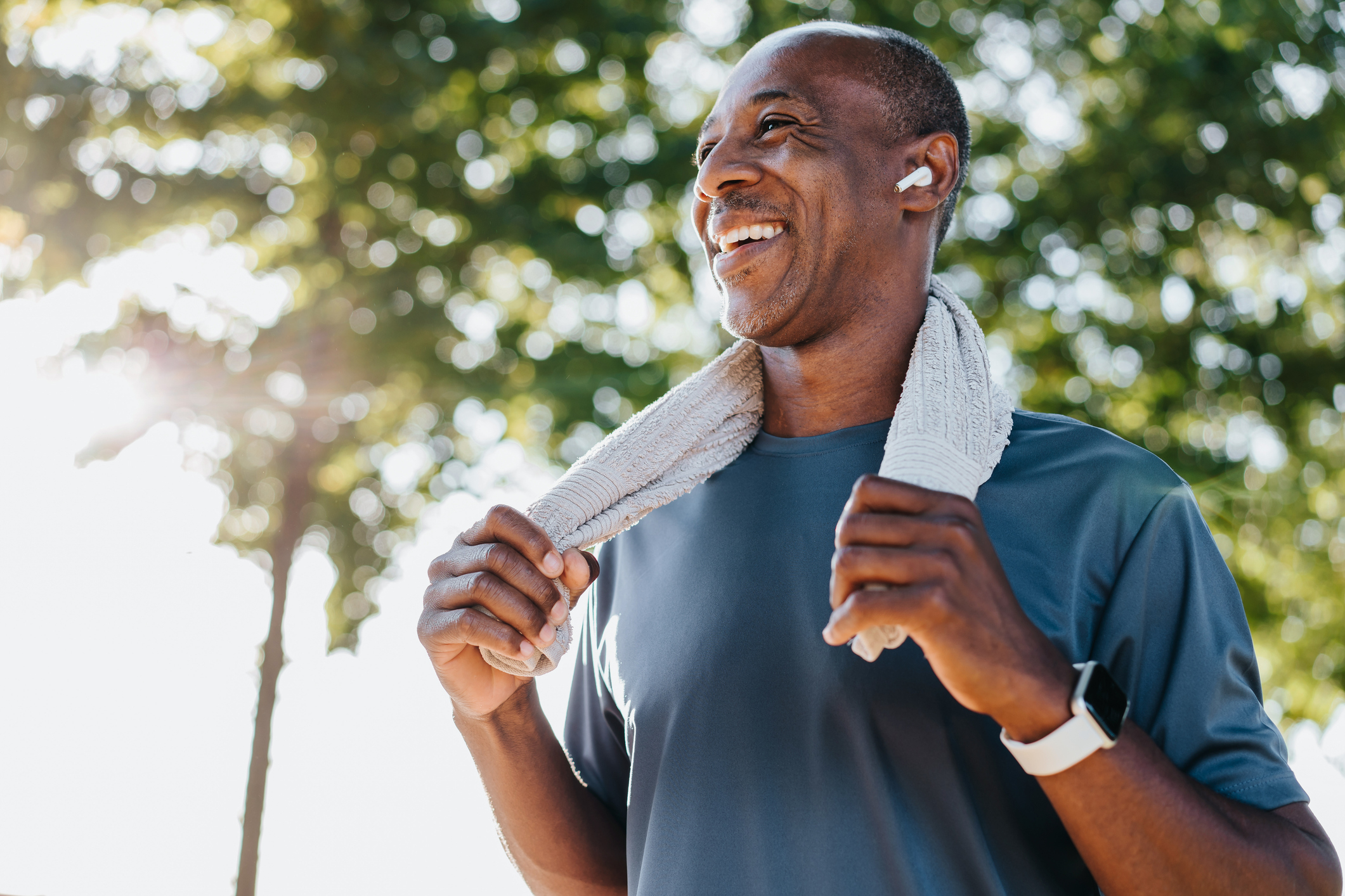 A man outdoors with a towel around his neck after a workout