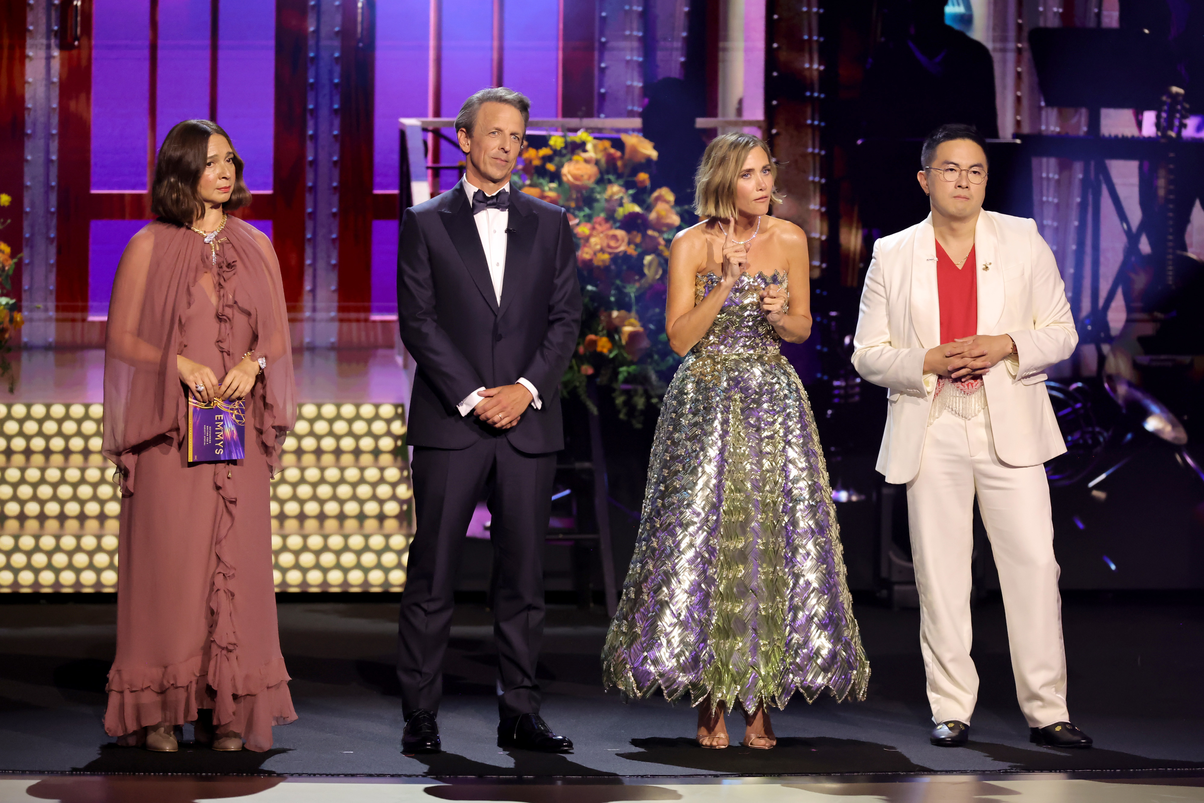 Maya Rudolph, Seth Meyers, Allison Janney, and David Alan Grier stand on stage at an event. Maya wears a flowing dress, Allison wears a glittering gown