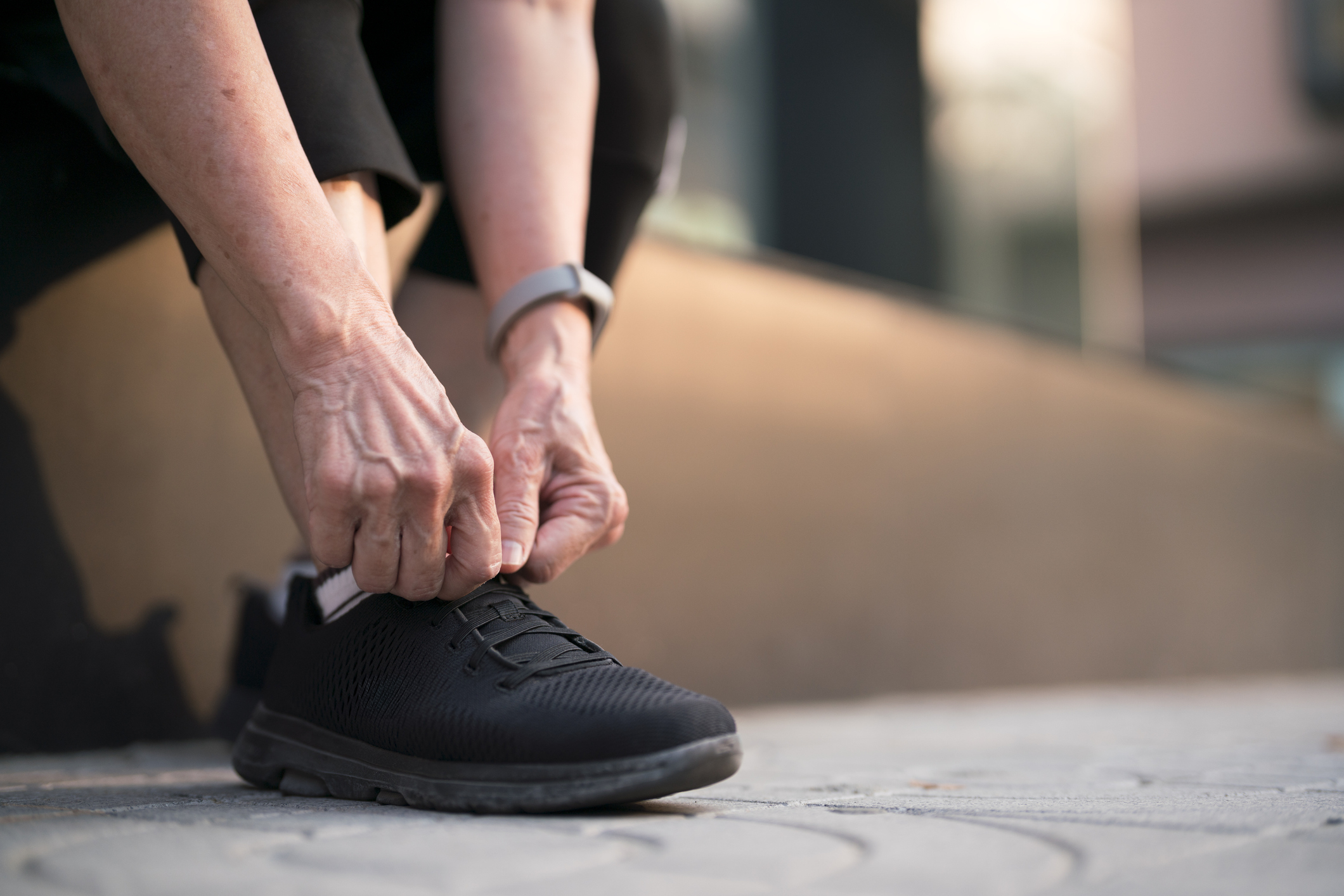 Person tying the laces of a running shoe, preparing for physical activity