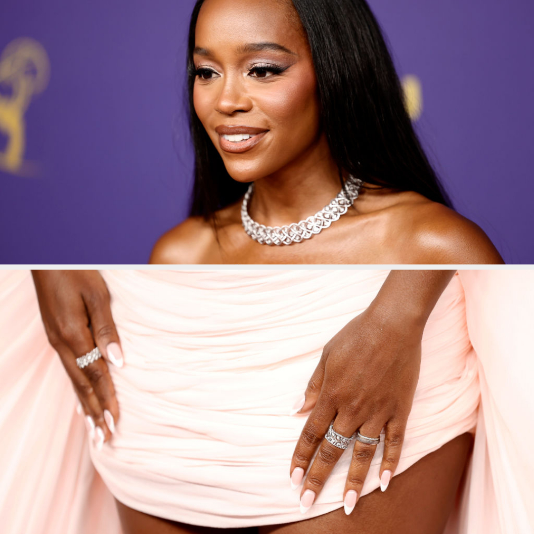 Aja Naomi King wearing a strapless gown with a diamond necklace, showcasing her manicured nails and multiple rings at a celebrity event