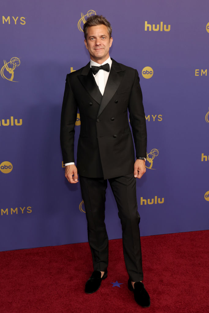 Joshua Jackson on the red carpet at the Emmys, wearing a classic black tuxedo with a bow tie and velvet loafers