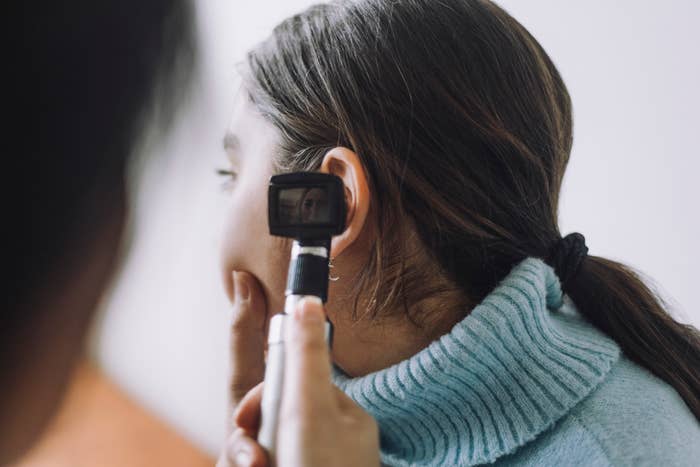 A medical professional examines a woman's ear with an otoscope during a check-up