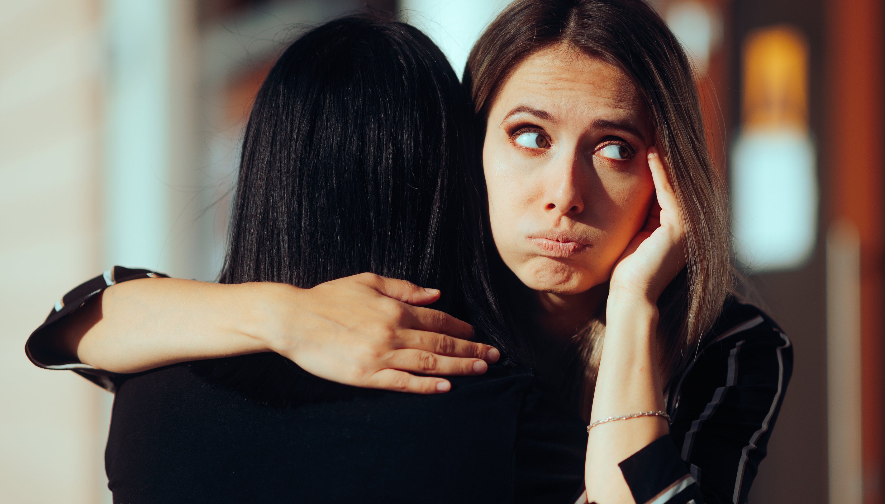 Two people hugging, one facing away, the other with a worried expression.