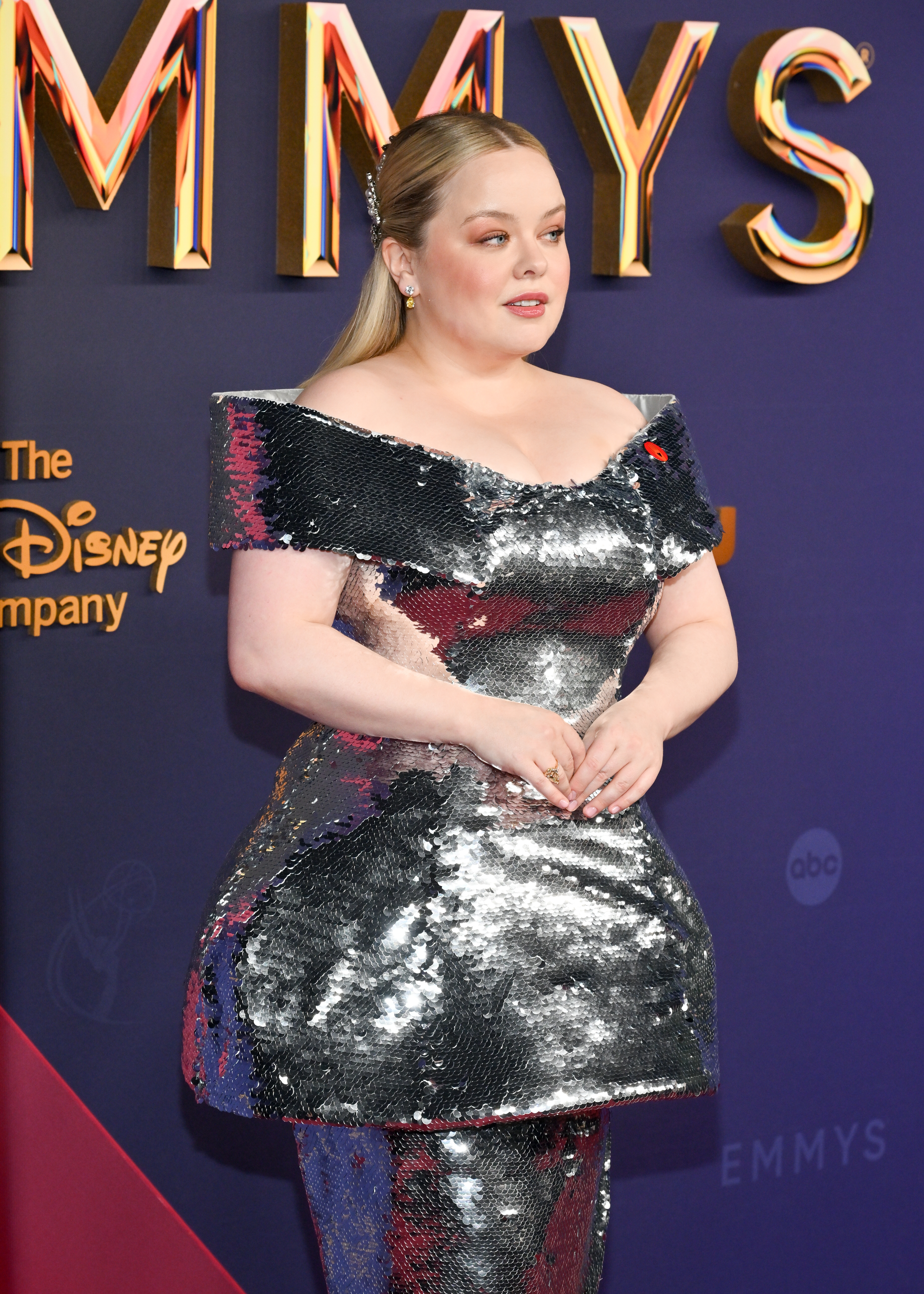 Nicola Coughlan on the red carpet at the Emmys, wearing a shiny silver, off-the-shoulder gown with a structured silhouette