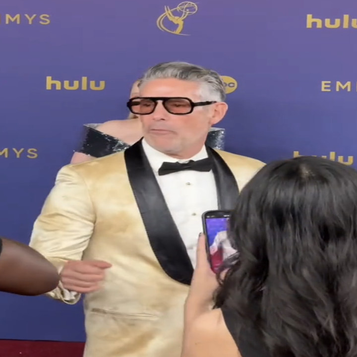 Man in light-colored suit with sunglasses on red carpet, signing autographs at Hulu Emmys event. TikTok UI with several other video thumbnails visible. Names unknown