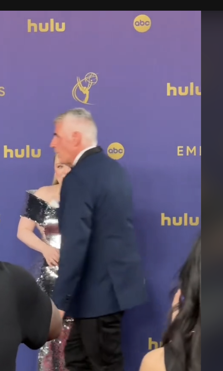 A person walking in front of Nicola Coughlan on the Emmys red carpet