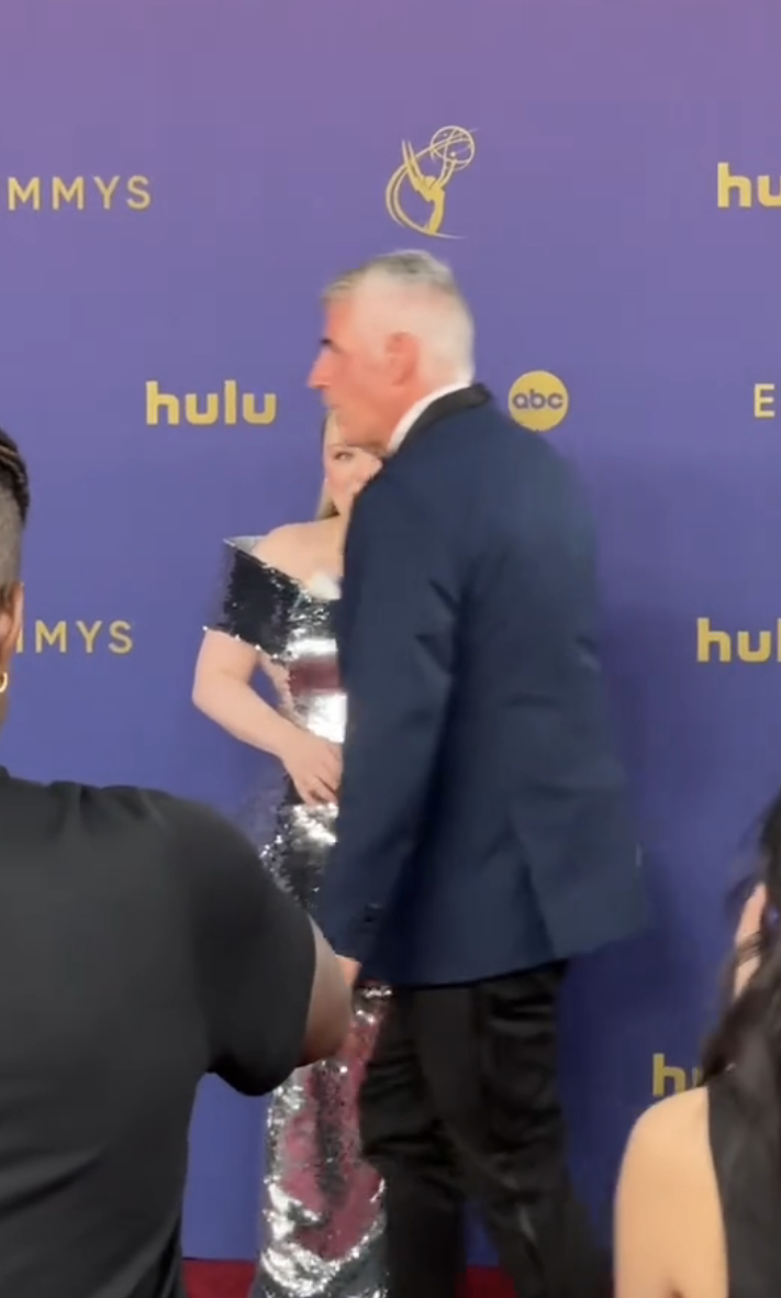 A person walking in front of Nicola Coughlan on the Emmys red carpet