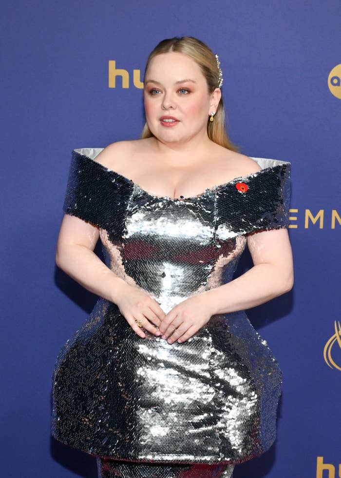 Nicola Coughlan on the red carpet wearing a metallic silver off-shoulder dress with structured design elements