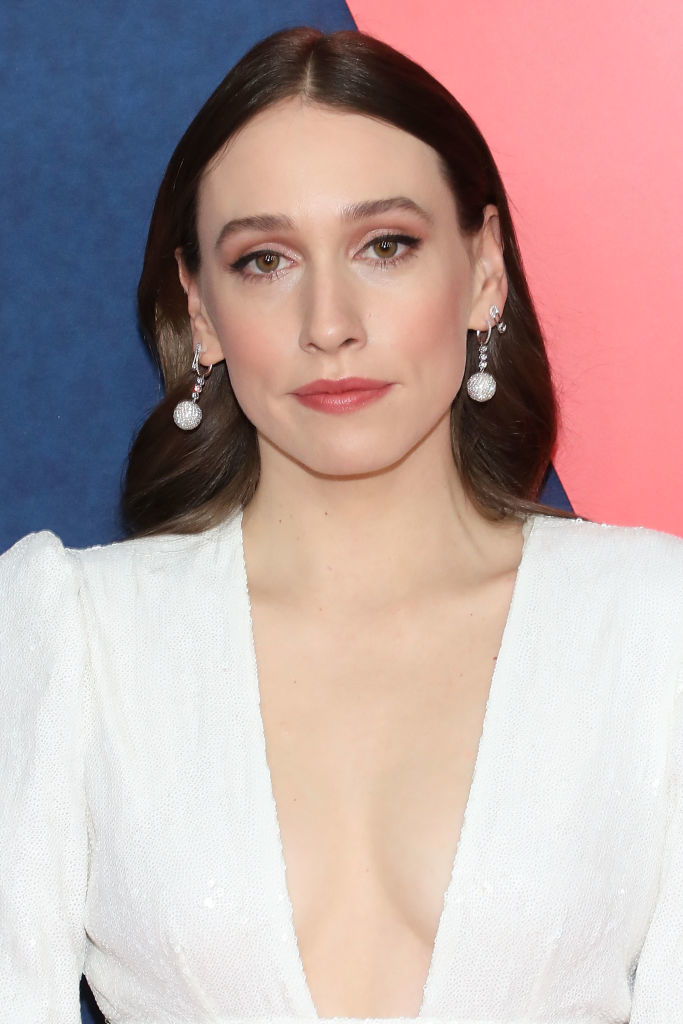 I don't know who this is. A person with long hair is pictured at an event, wearing a deep V-neck white dress and elegant drop earrings