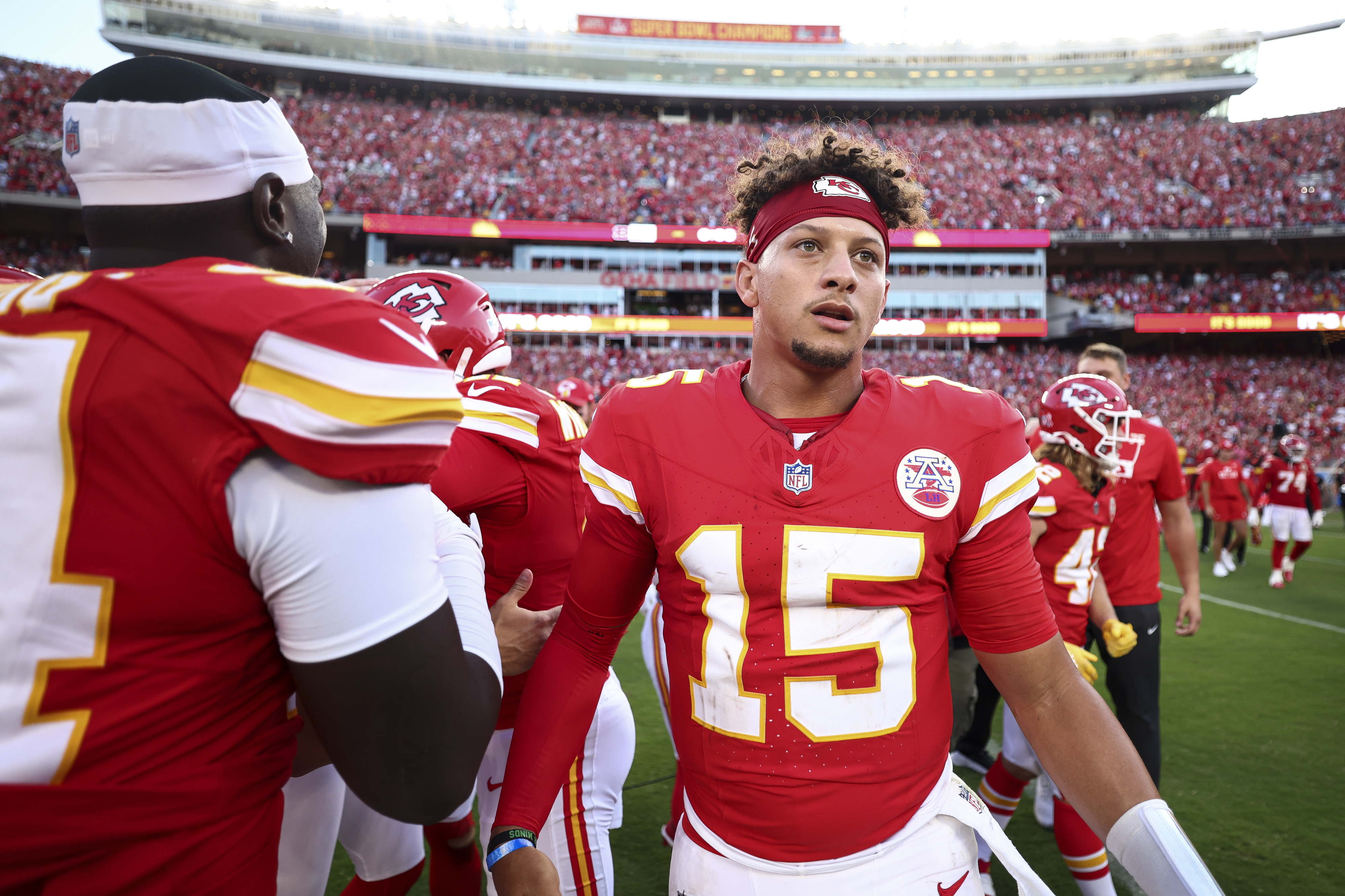 Patrick Mahomes in a football jersey with the number 15, surrounded by teammates in a stadium full of fans
