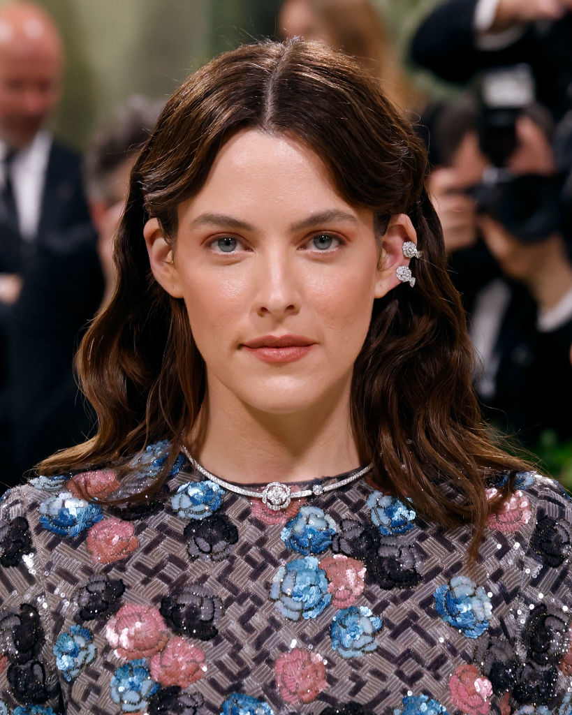 Riley Keough at an event, wearing a floral embellished dress