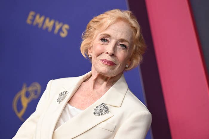 Holland Taylor on the red carpet at the Emmys, wearing a stylish tailored white blazer with brooches on each lapel