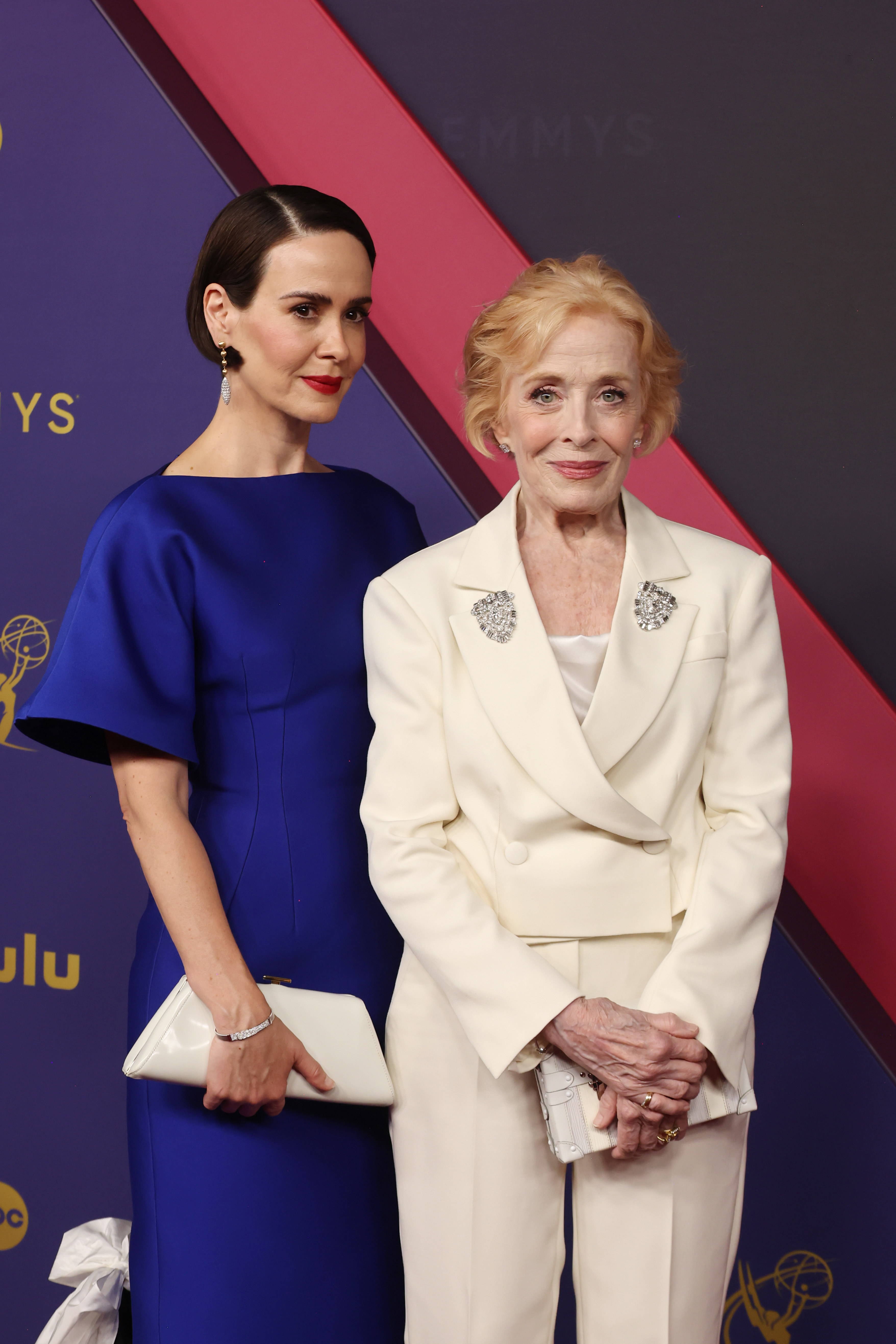 Sarah Paulson in a sleek dress and Holland Taylor in a tailored suit pose together at an event