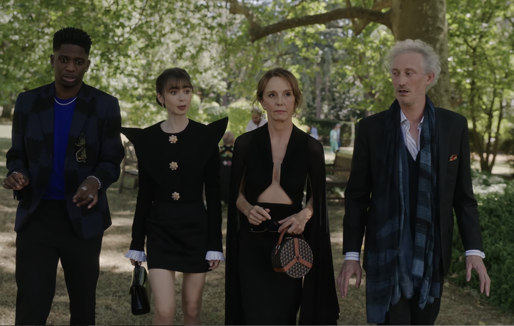 Lucas Bravo, Lily Collins, Philippine Leroy-Beaulieu, and Samuel Arnold are walking outdoors in formal attire