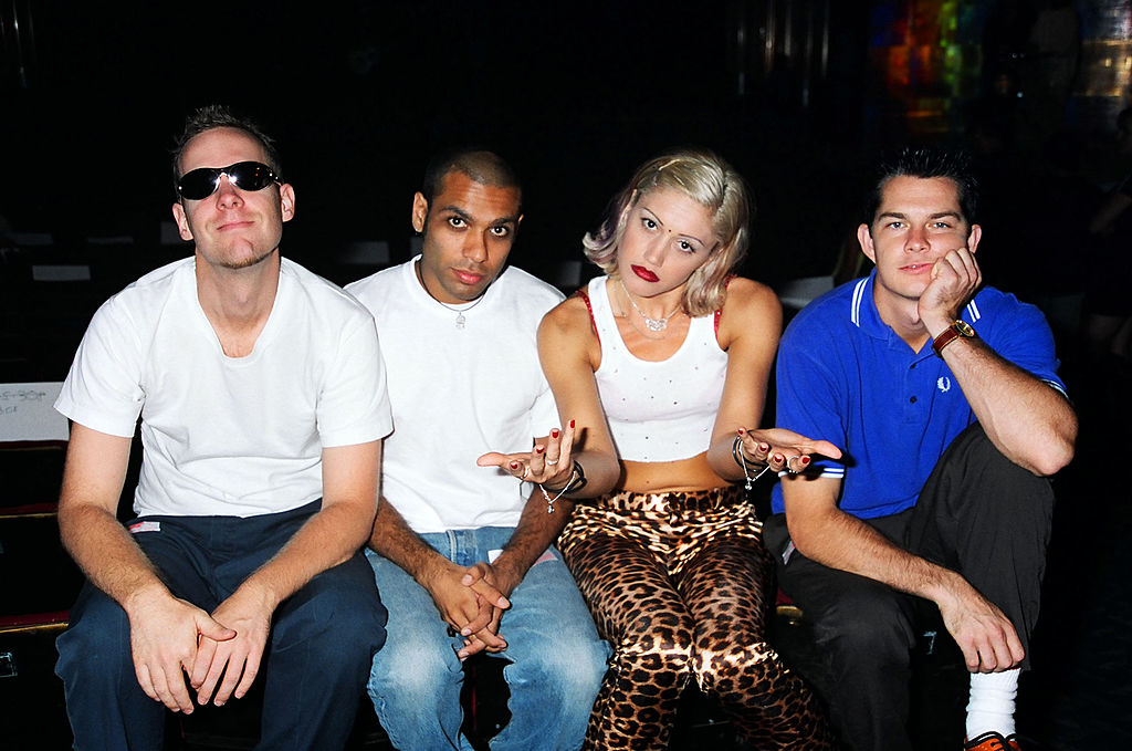 Adrian Young, Tony Kanal, Gwen Stefani, and Tom Dumont of No Doubt pose casually; Gwen wears a white top and animal print pants