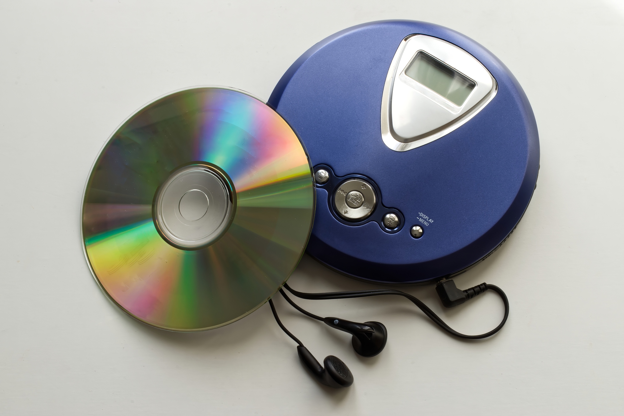 A CD player with attached earbuds placed next to a CD