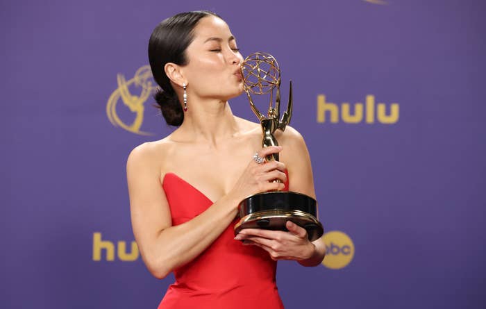 Anna Sawai kissing her Emmy in a red dress