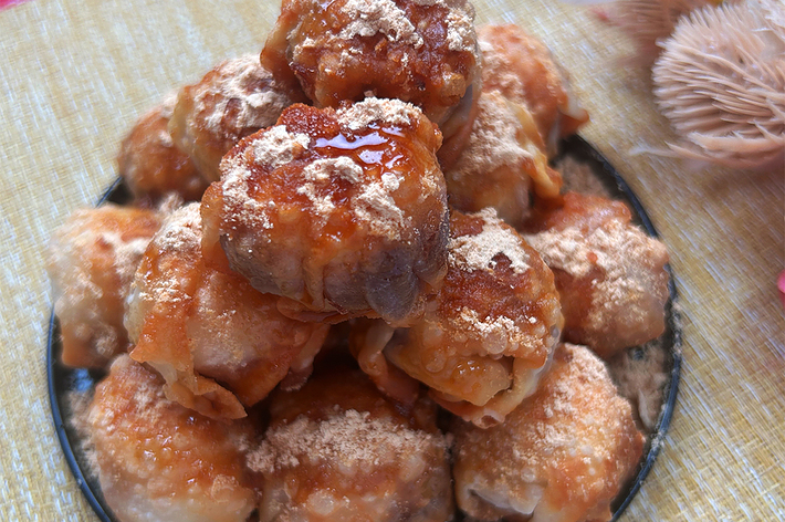 たくさんのパイが皿に山盛りに盛られており、上には黒蜜がかかっています。右上には飾りの花が見えます。