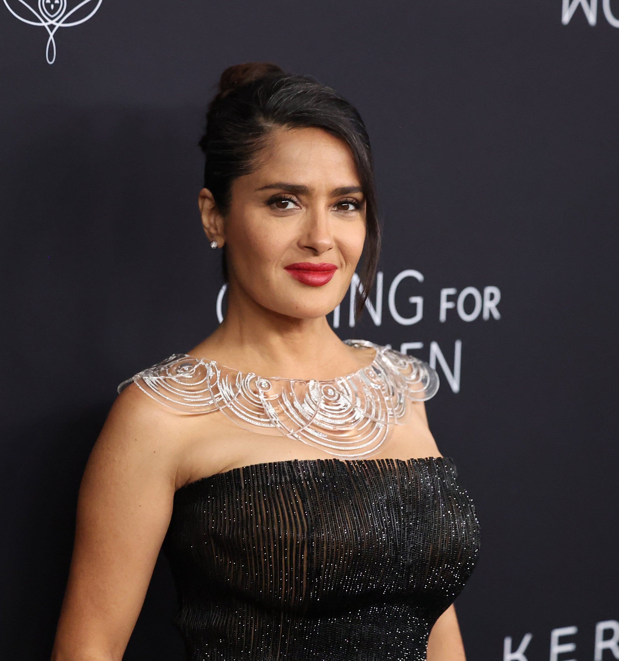 Salma Hayek poses in an elegant off-shoulder dress with intricate neck detailing at a Kering Foundation event