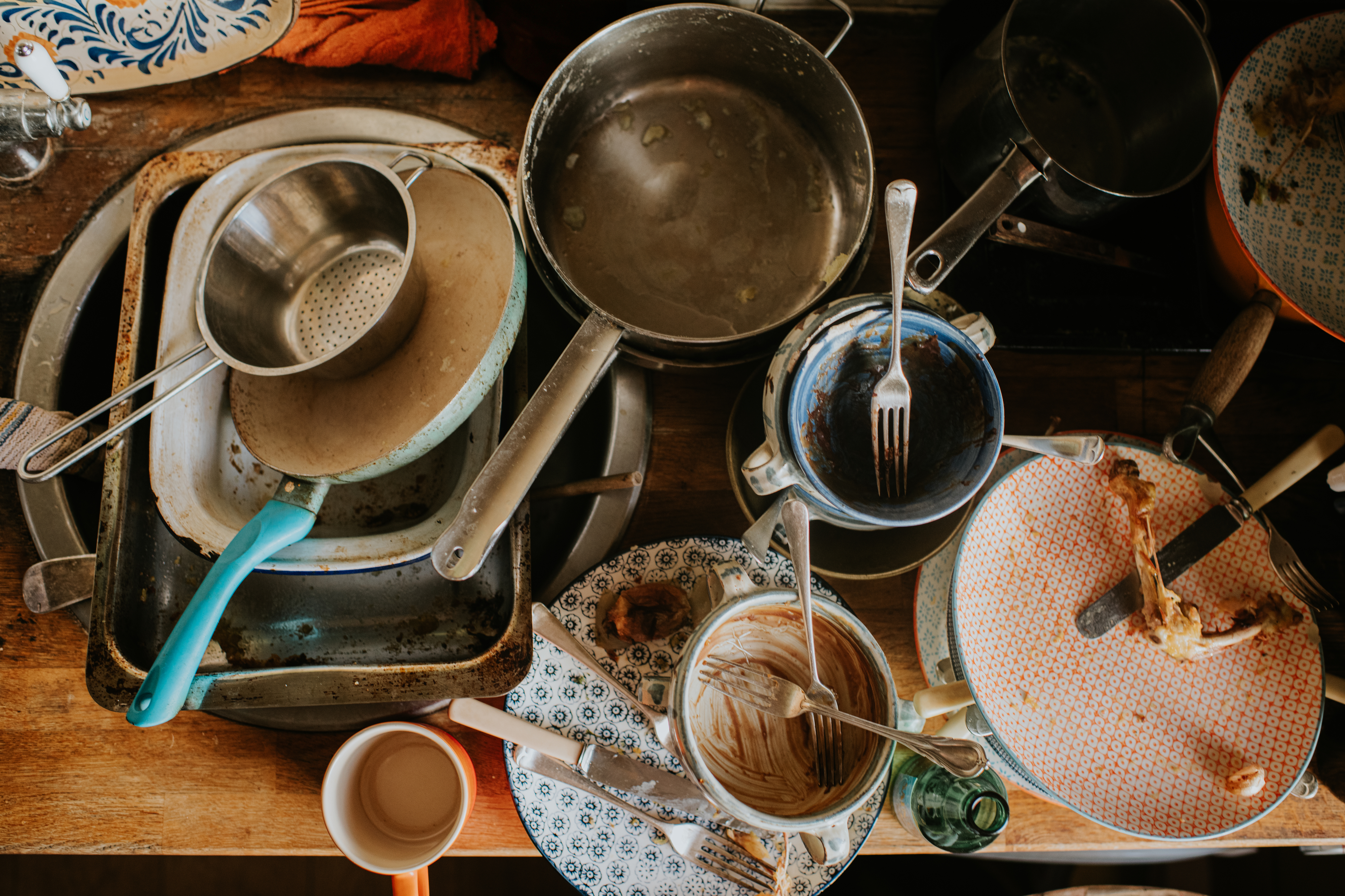 A cluttered kitchen counter full of dirty pots, pans, plates, and utensils, displaying an unwashed mess after cooking
