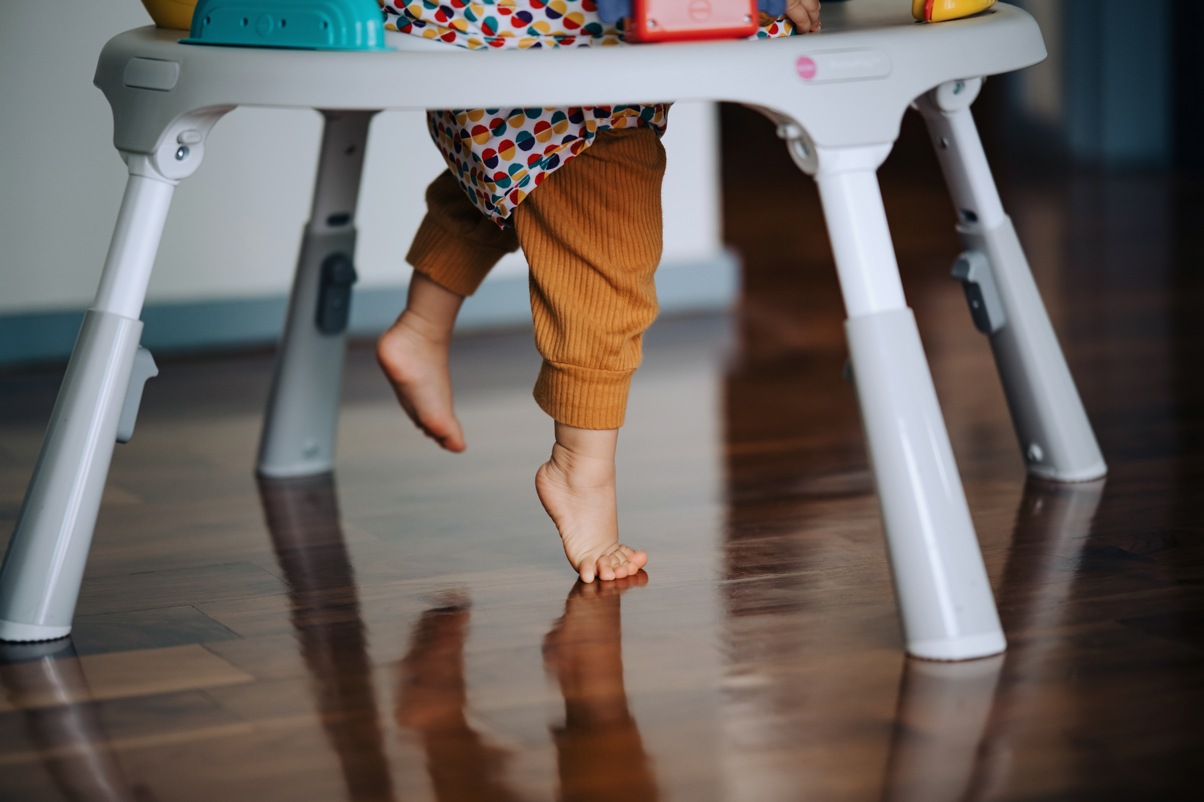 A toddler's feet are seen standing in a baby walker