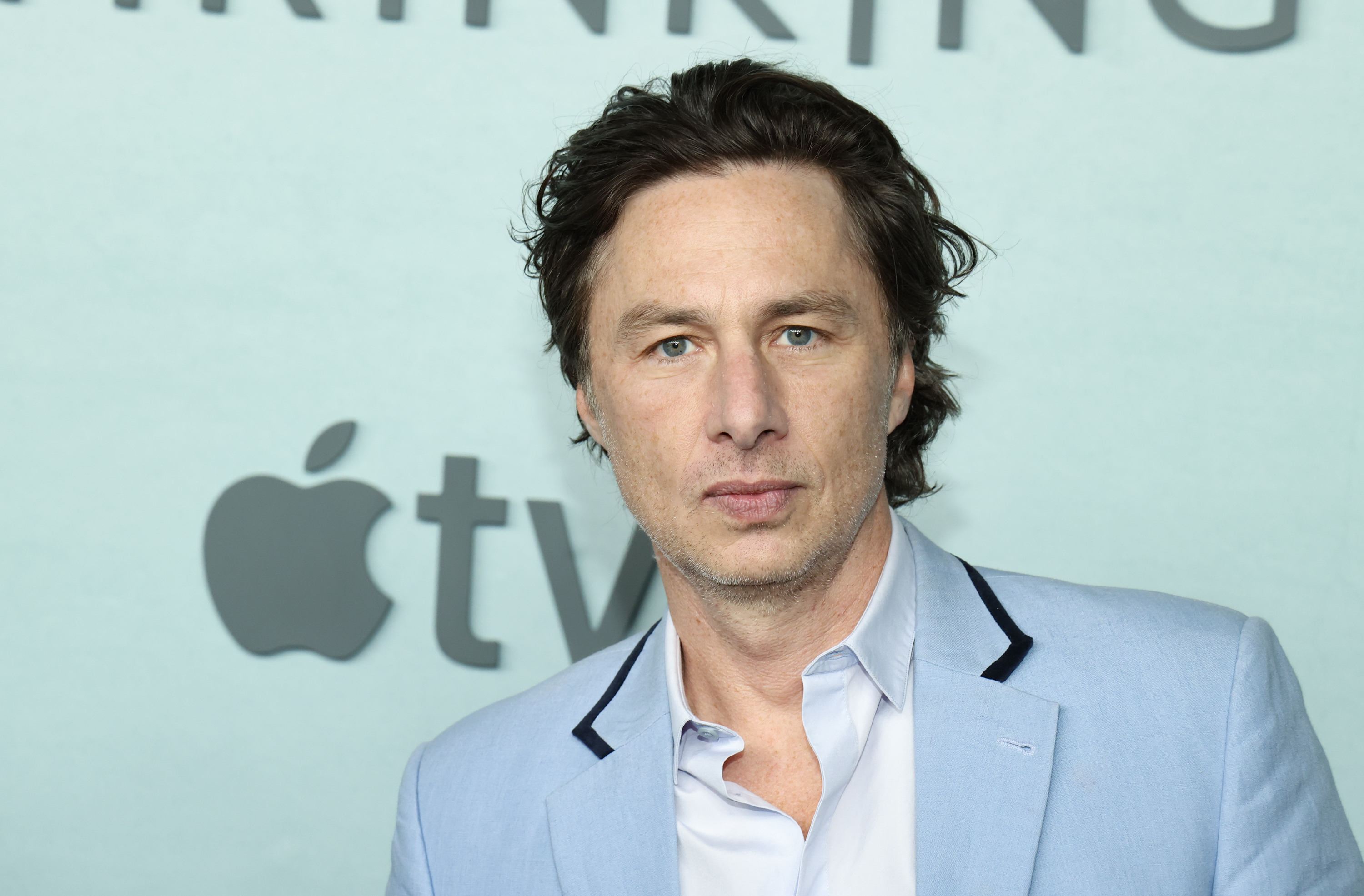 Zach Braff at an event hosted by Apple TV+. He is wearing a light blazer and an open-collared shirt
