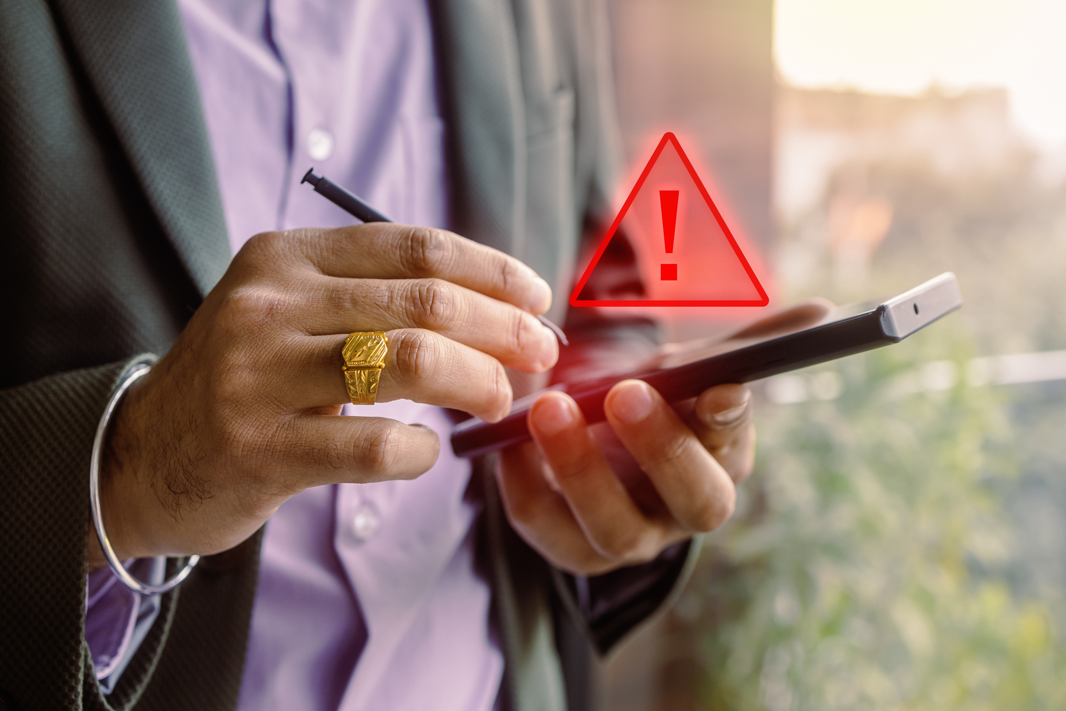 A person in business attire uses a stylus on a tablet, with a red warning symbol on the screen