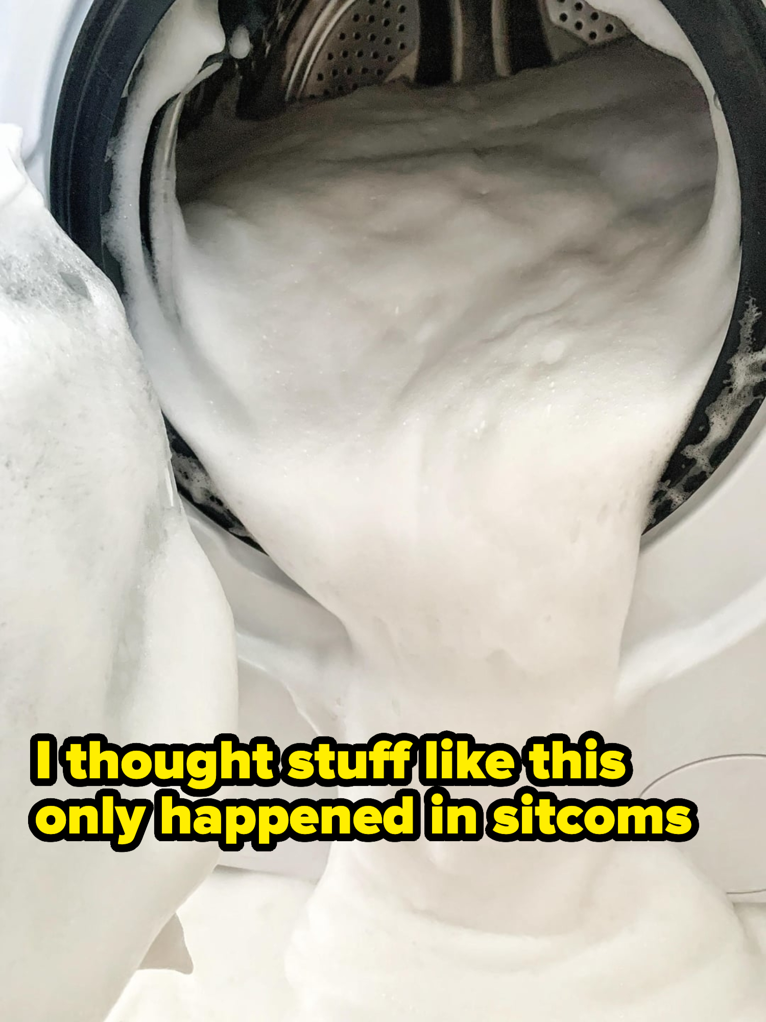 Washing machine overflowing with soap suds, spilling onto the floor