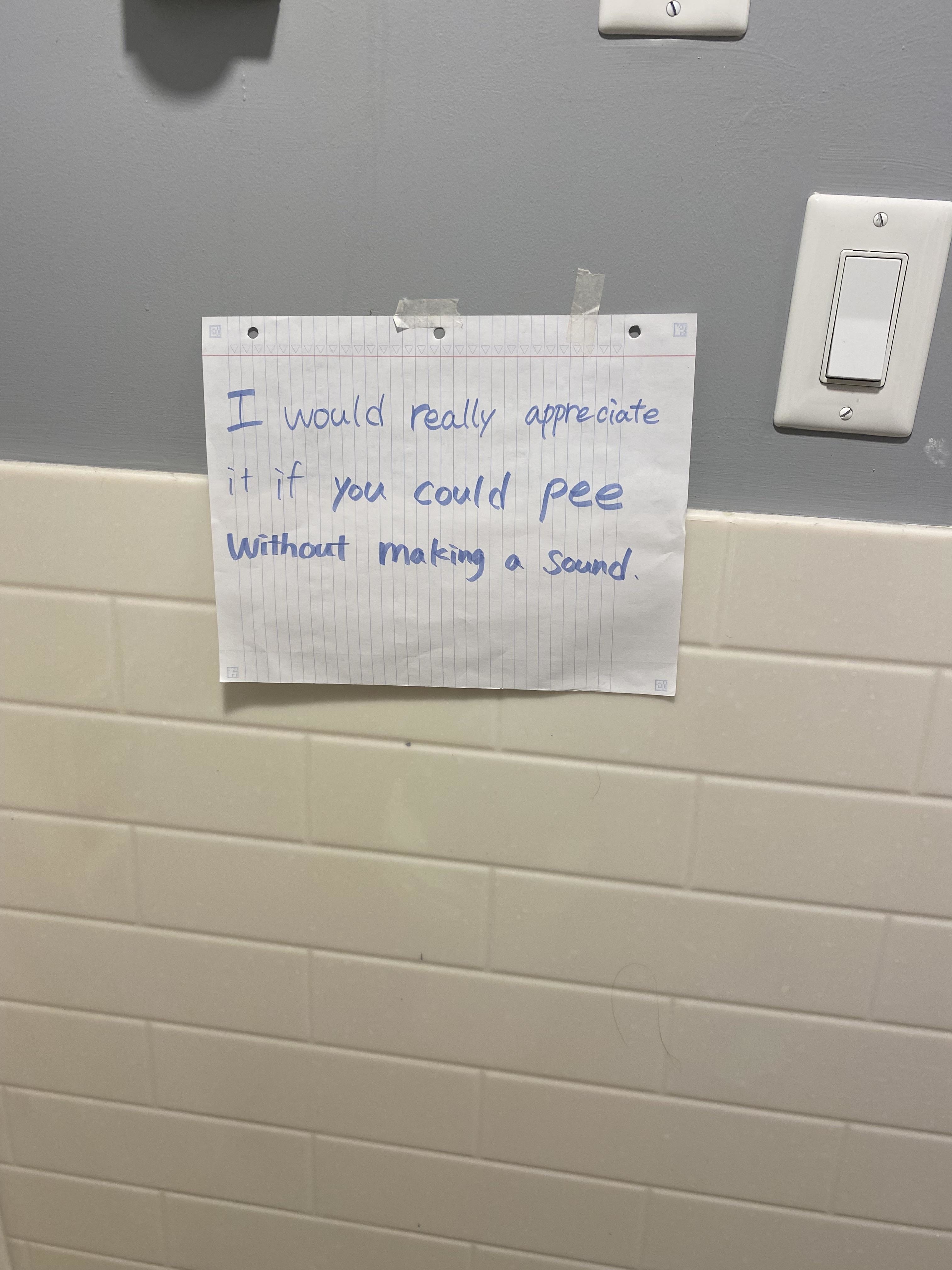 Handwritten note taped to the wall that reads: "I would really appreciate it if you could pee without making a sound."