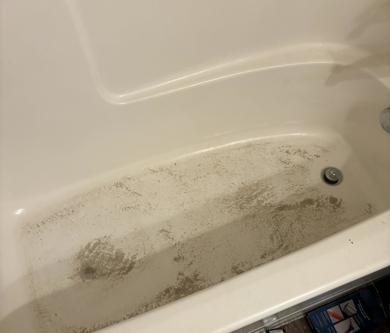 Dirty bathtub with cat litter and stains on the surface
