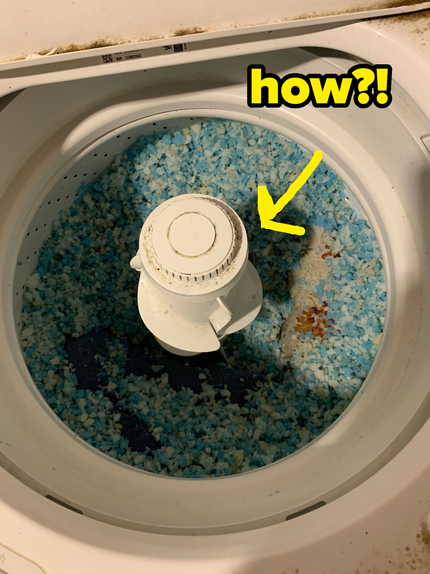 Top-down view of the inside of a washing machine filled with pieces of blue material from a disintegrated pillow