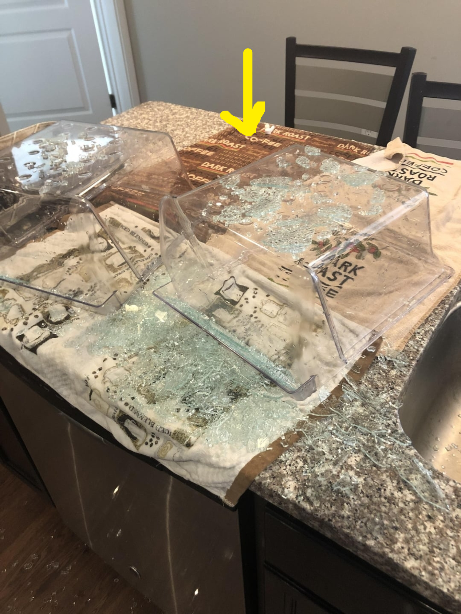 Glass shards and broken glass containers on a kitchen counter with towels underneath