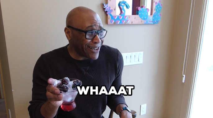 A man sits at a table holding a bowl of berries with a surprised expression. Large text in the image says, WHAAAT