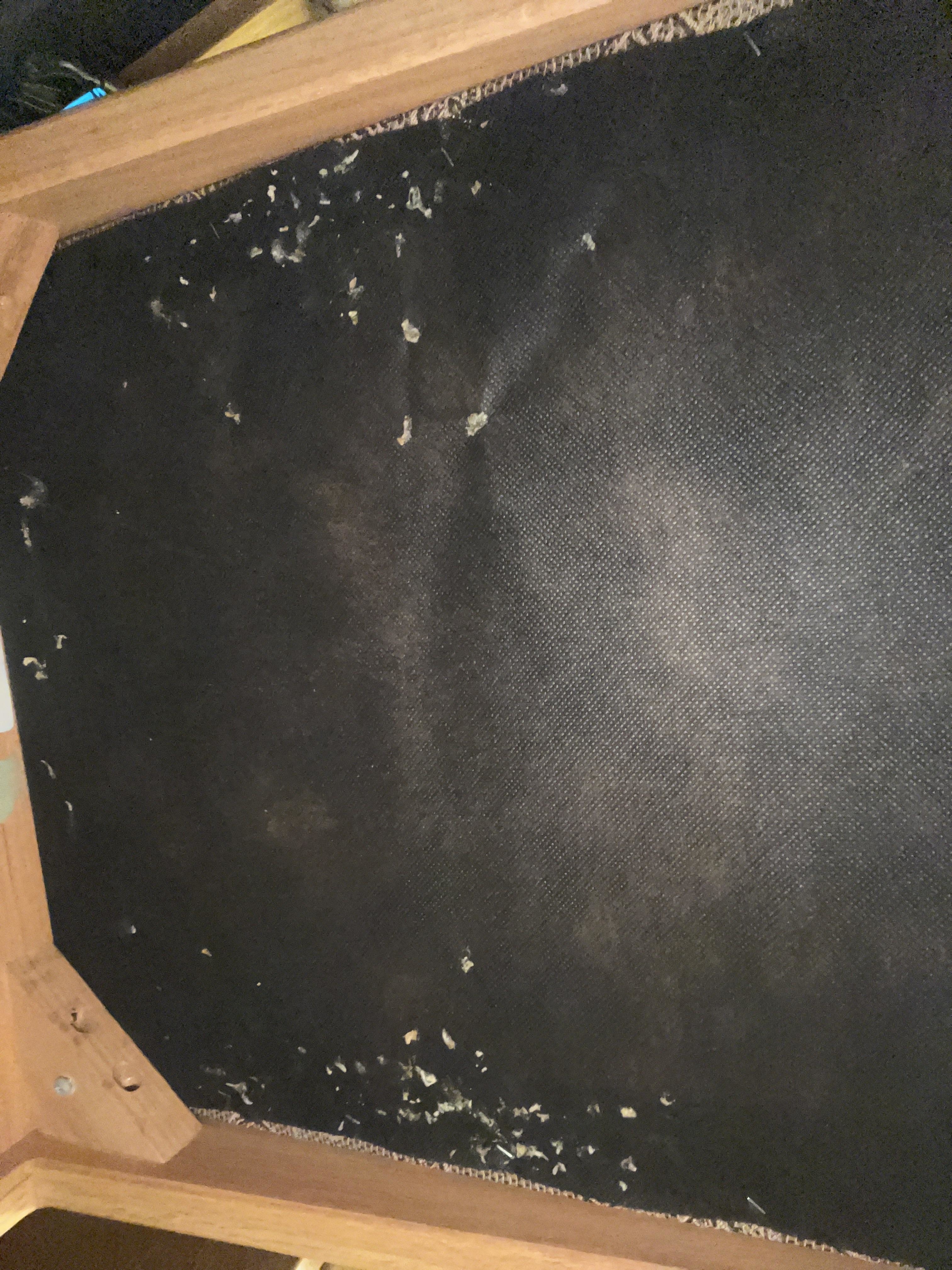 The image shows the underside of a piece of furniture with visible damage to the material