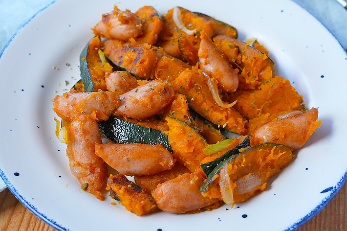 お皿に盛り付けられた調理済みの肉と野菜の料理。フォークが横に置かれている。