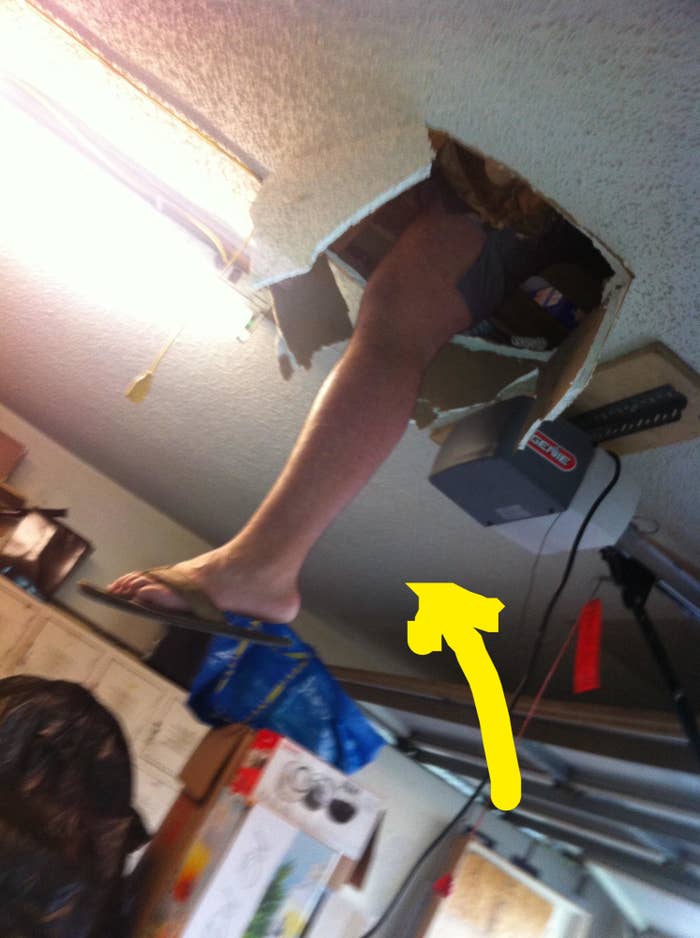 A person has accidentally fallen halfway through a ceiling, with one leg and foot in a flip-flop dangling through a hole in the ceiling