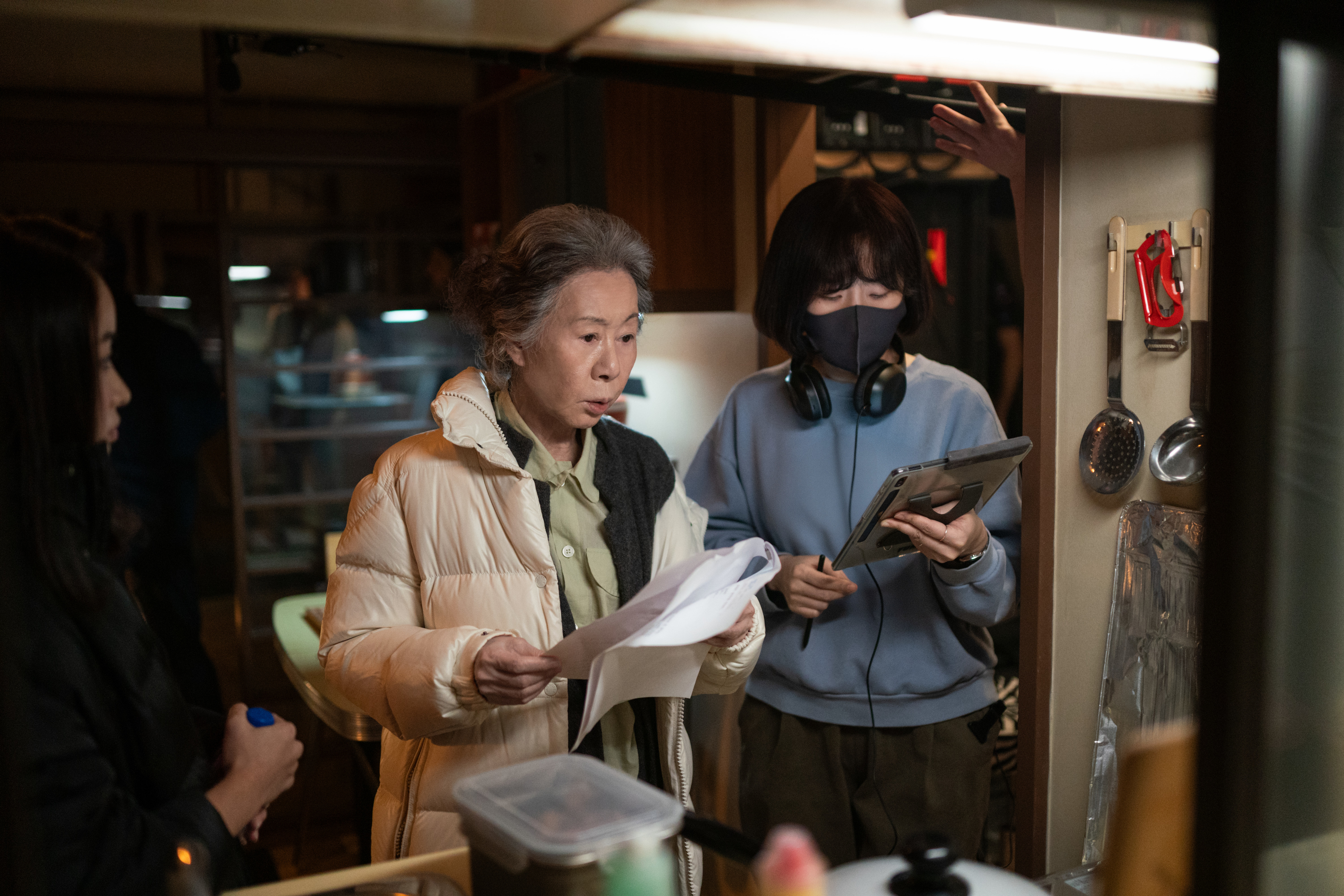 Youn Yuh-jung and director in a kitchen set, reviewing a script