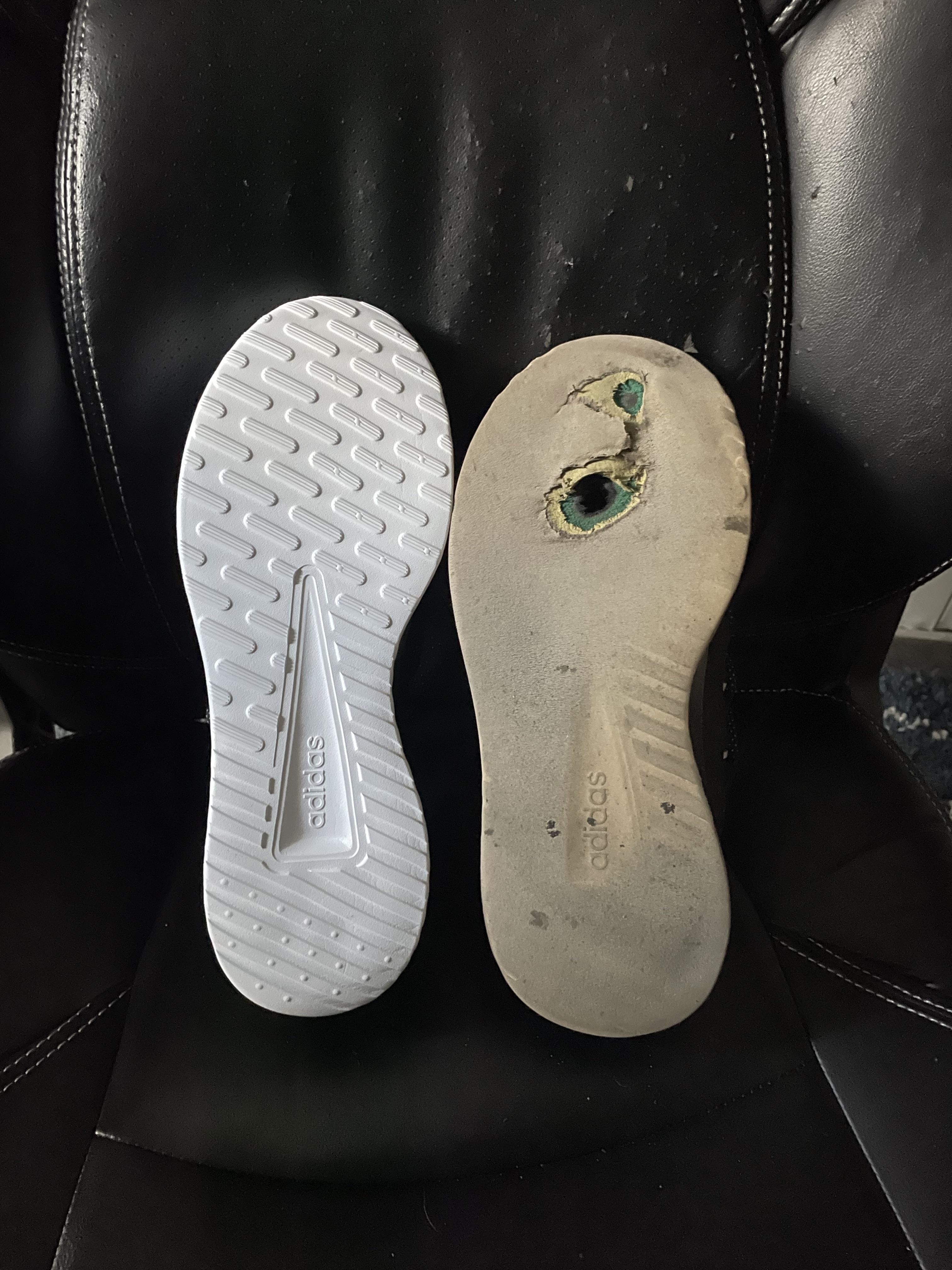 Two Adidas shoe soles placed side by side, one new and clean, the other worn and damaged with holes