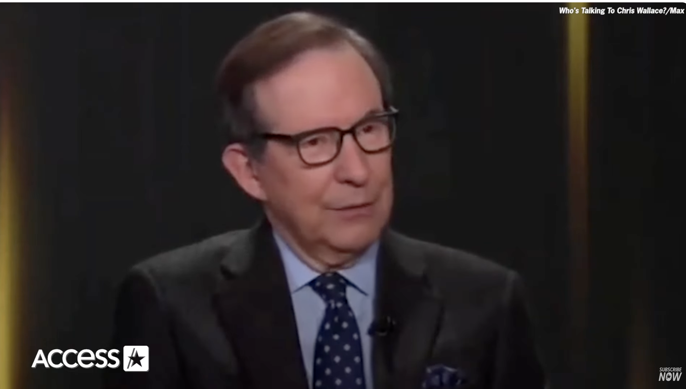 Chris Wallace appears on the set of "Access NOW" during an interview, wearing a dark suit with a white-collared shirt and a polka dot tie