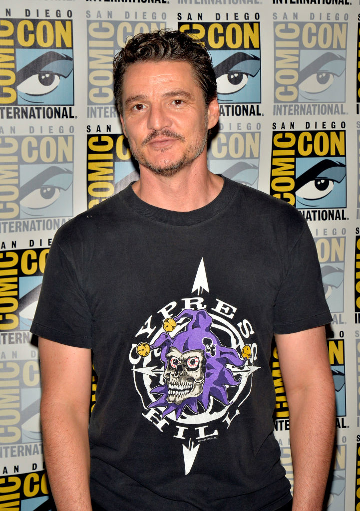 Pedro Pascal in a Cypress Hill t-shirt poses in front of a Comic-Con International backdrop