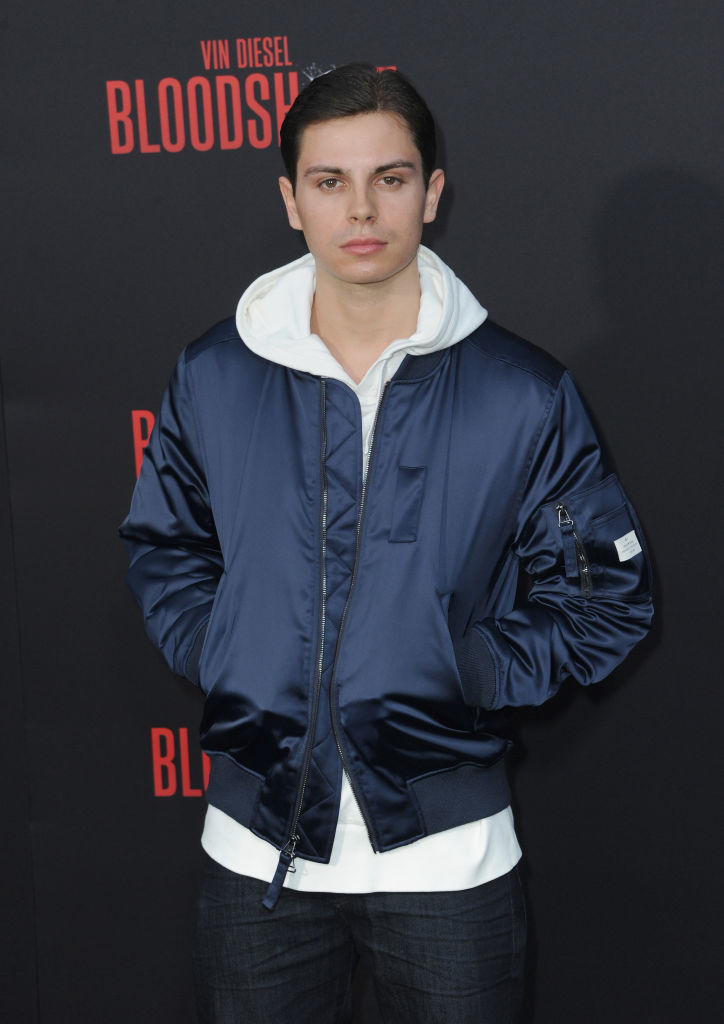 Jake T. Austin poses at an event for the film "Bloodshot" wearing a bomber jacket over a hoodie