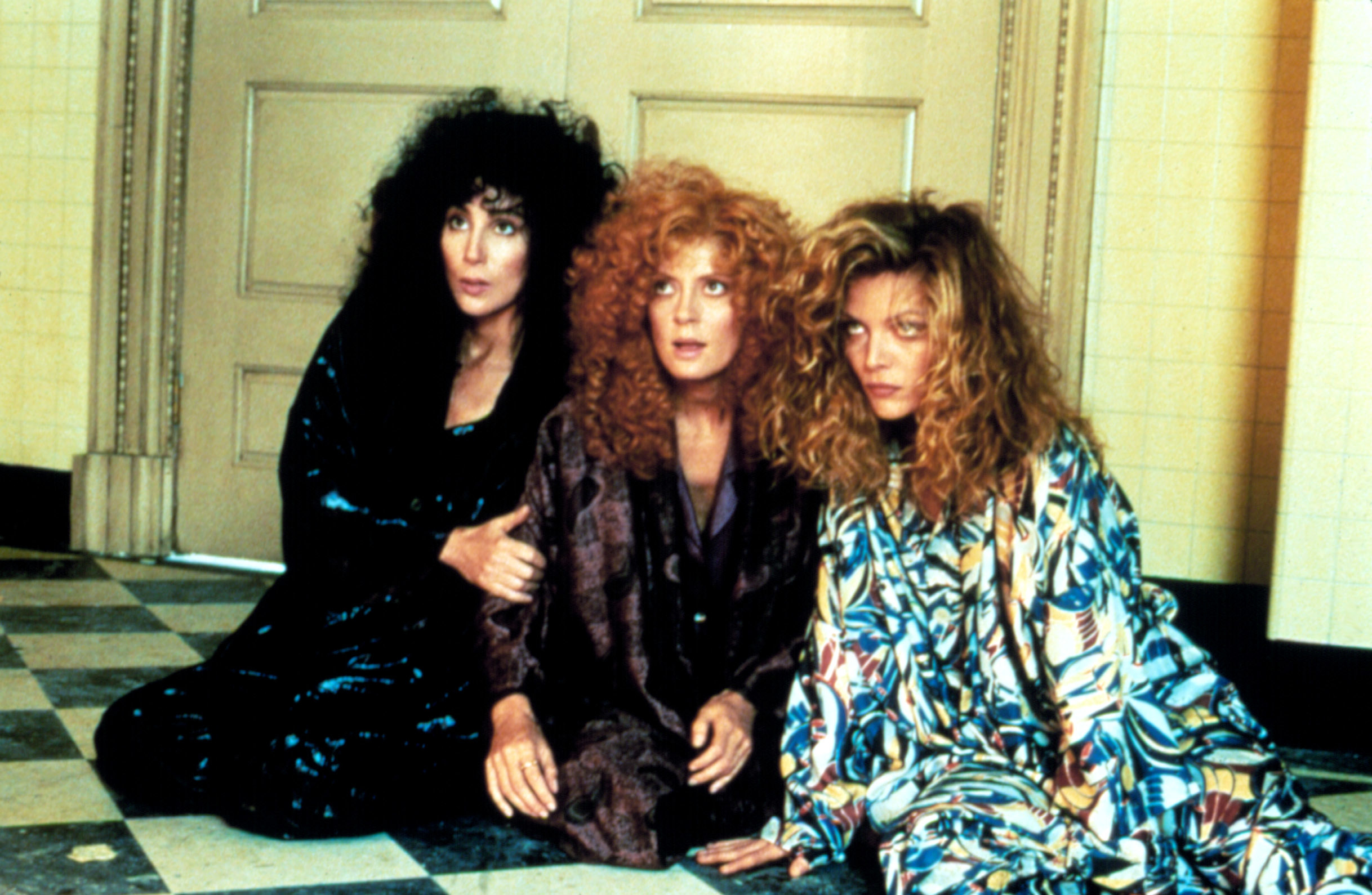 Cher, Susan Sarandon, and Michelle Pfeiffer sitting on the floor together in "The Witches of Eastwick"