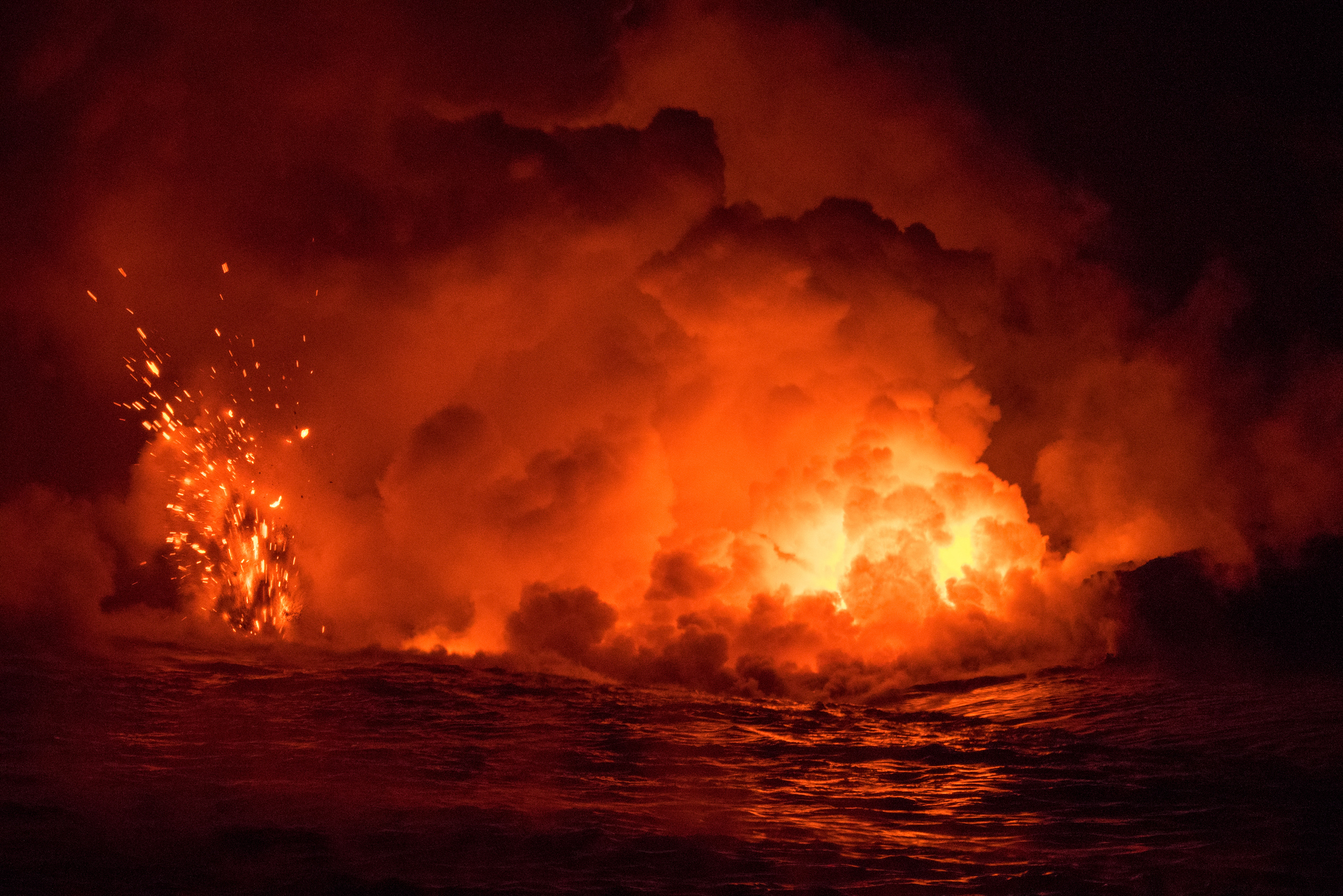 A powerful volcanic eruption with molten lava glowing and spewing sparks into the night sky, filling the scene with thick smoke and intense light