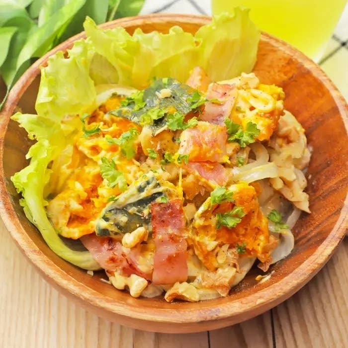 木製のボウルに野菜と卵が盛り付けられた料理。レタスの上にオムレツ風の具材とハーブがトッピングされている。
